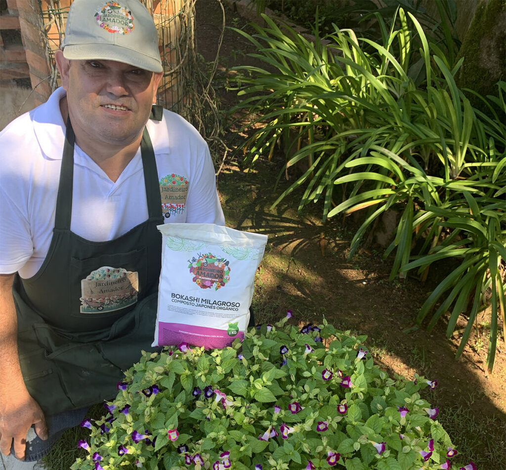 Altamir segurando um Bokashi ao lado De uma linda Planta